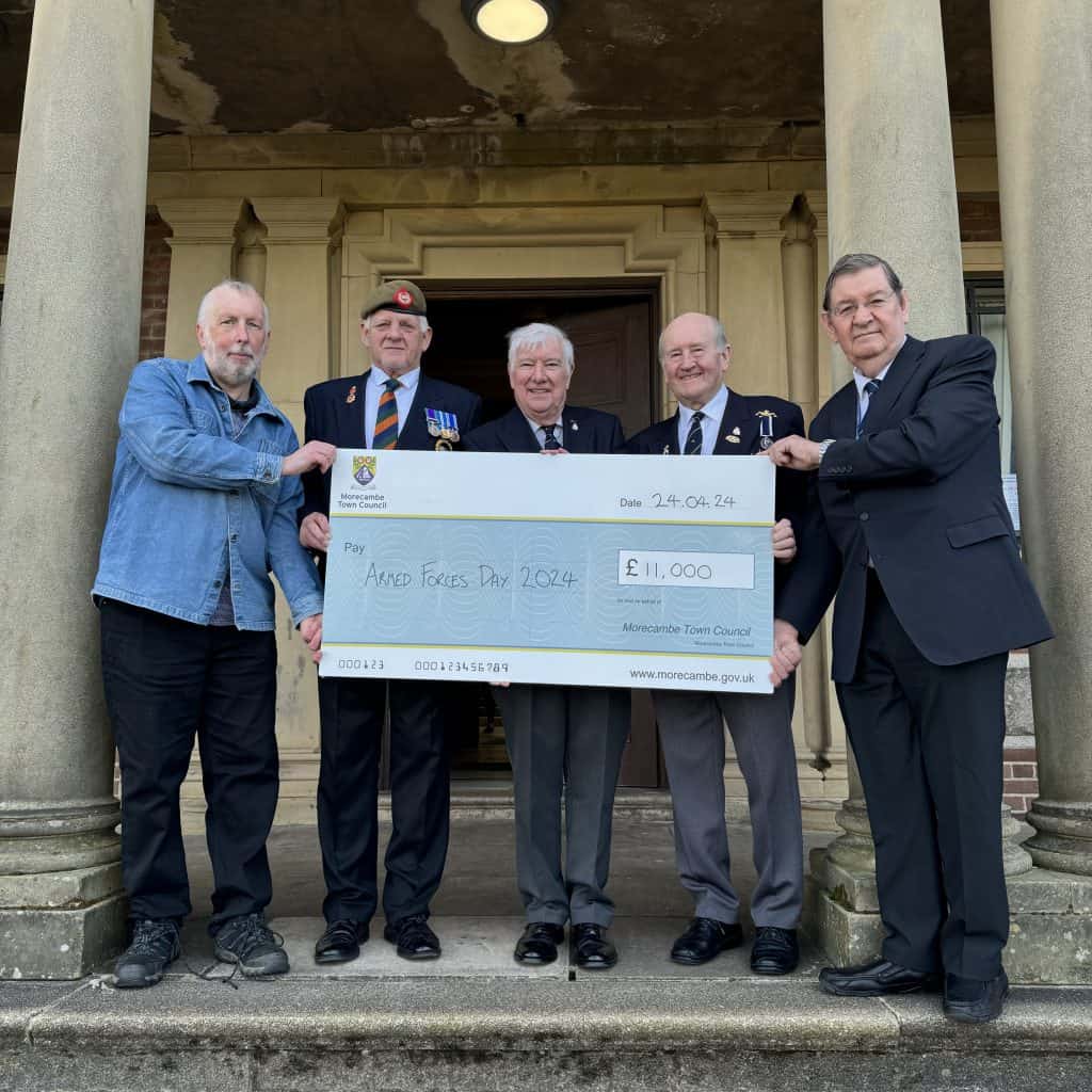 A photo of representatives from Morecambe and Lancaster Armed Forces Day 2024 accepting a cheque for £11,000 from Morecambe Town Council.